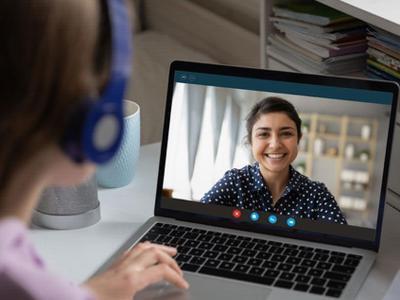 Person with headset viewing a video call on laptop.